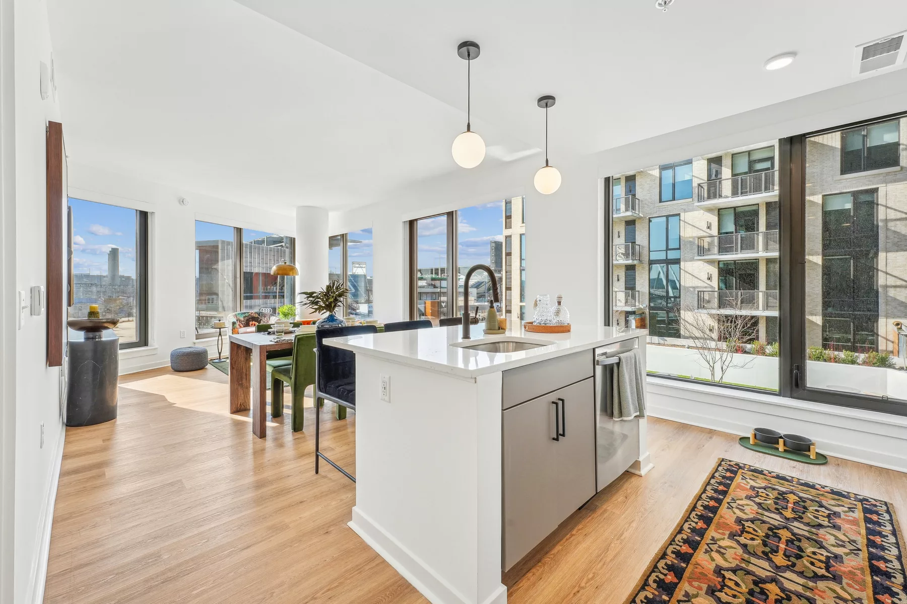 Open-concept kitchen and dining area with kitchen island, dining table and chairs, and large windows on two sides.