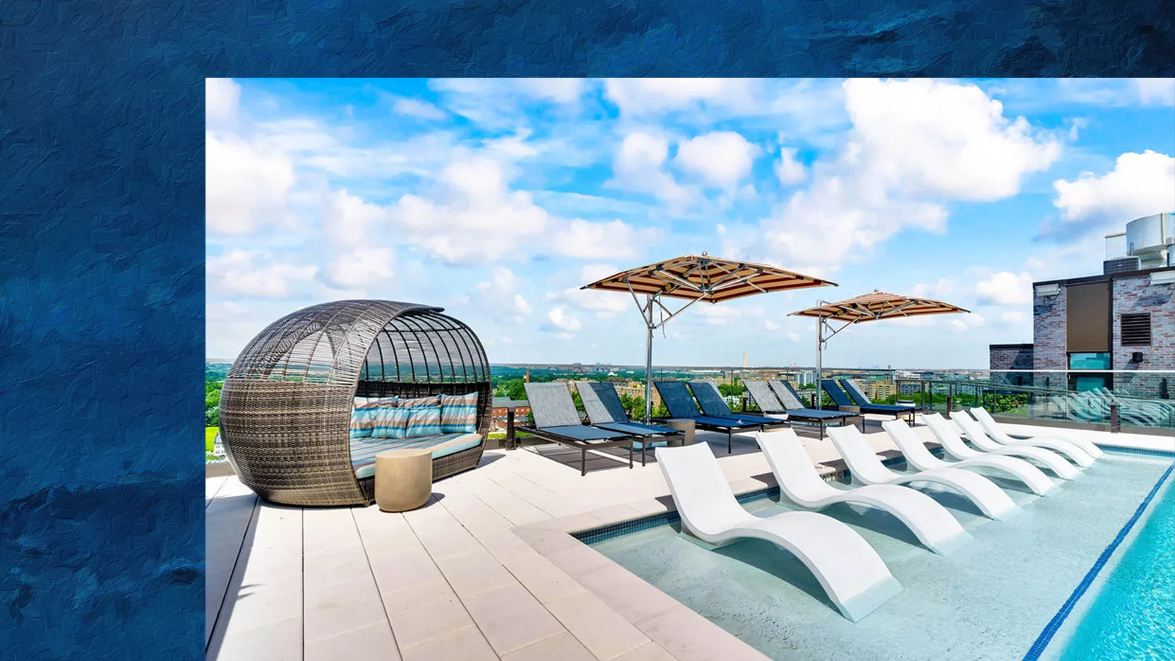 A photo of a rooftop pool with lounge chairs and umbrellas under a blue sky, with a textured blue border on the left side and top.