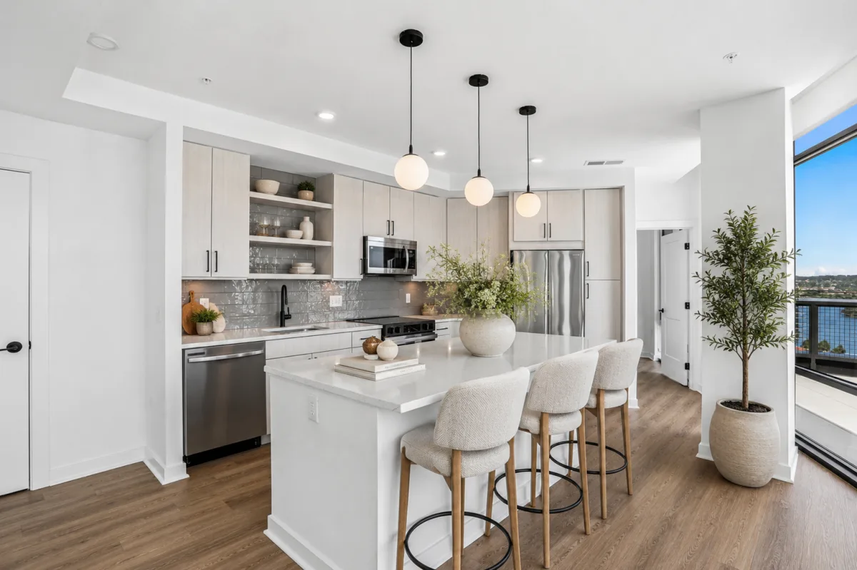 Modern kitchen with waterfall island, pendant lighting, and terrace views