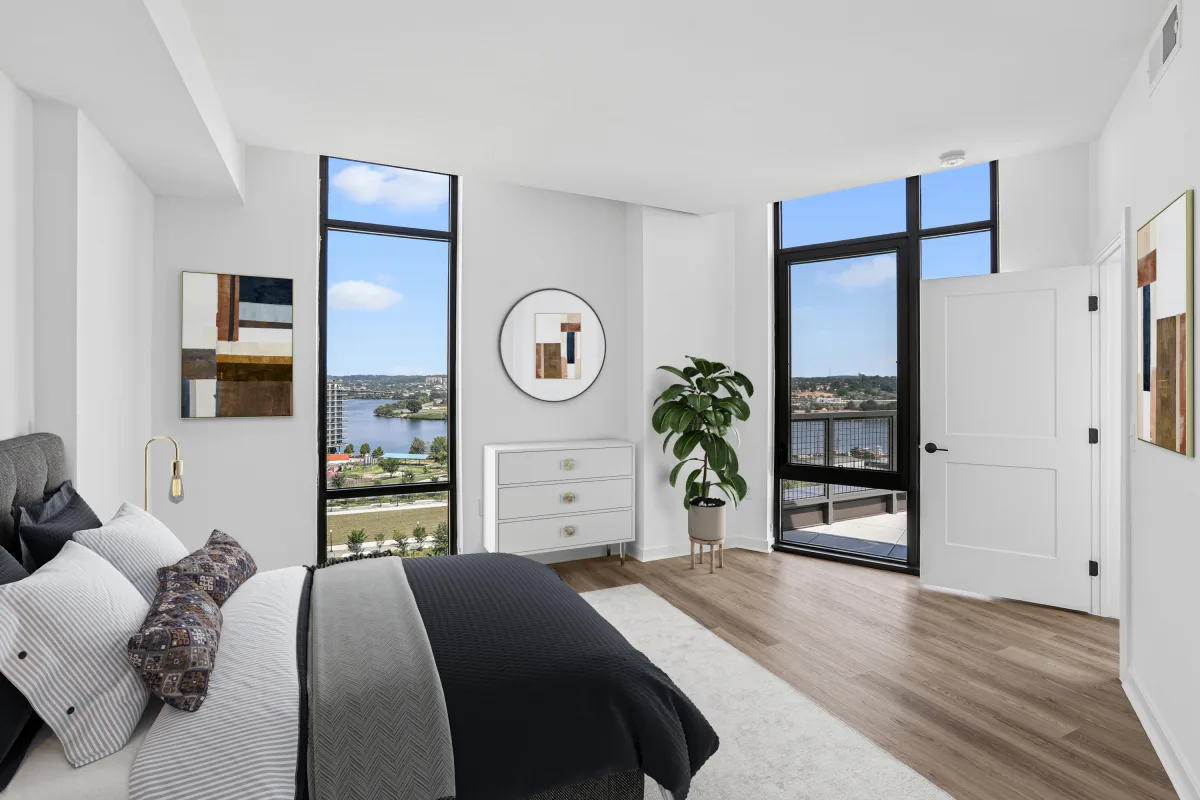 Spacious bedroom with balcony access, river views, and floor-to-ceiling windows